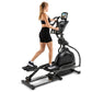 Woman using black Spirit XE795 elliptical machine with tablet display on white background