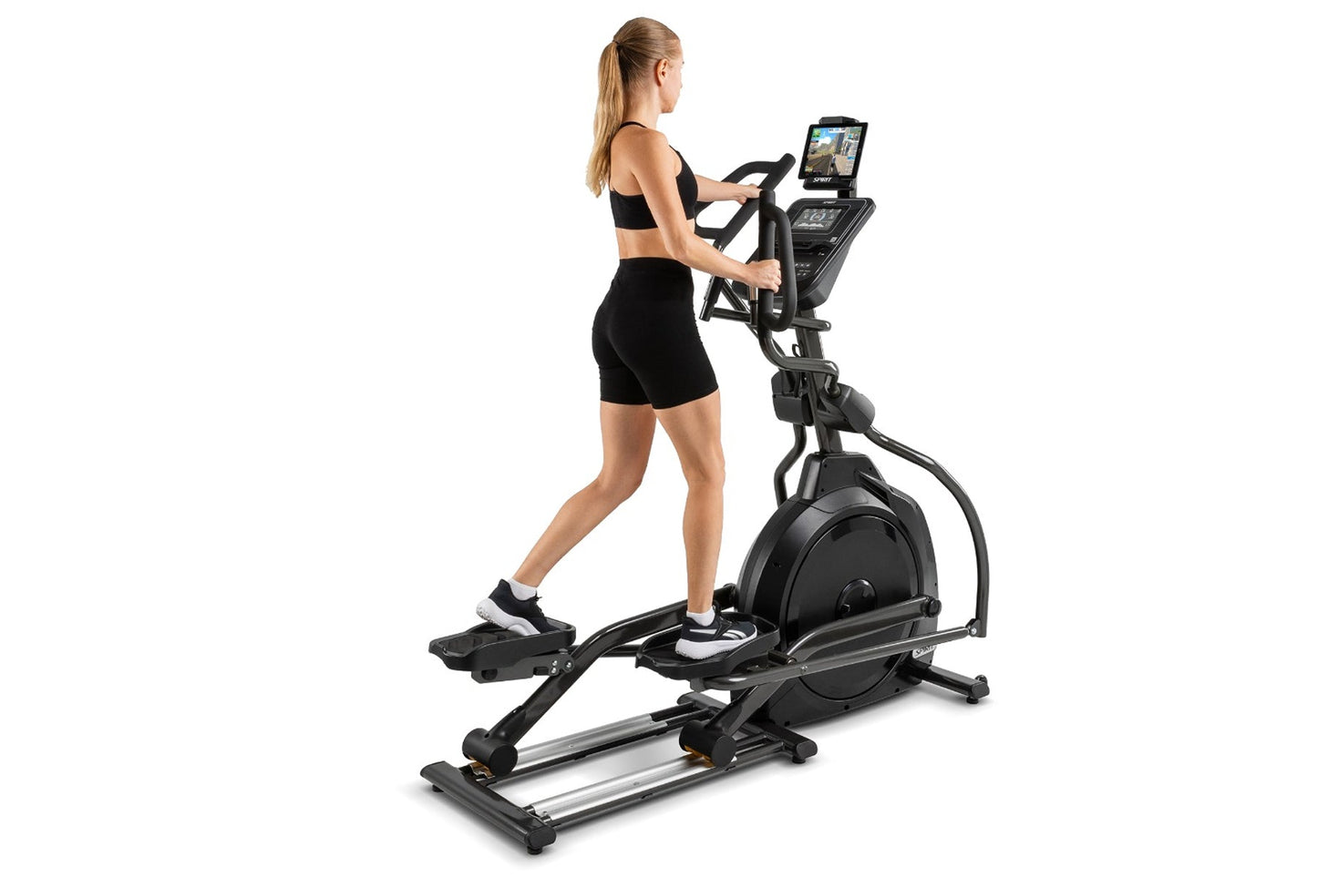 Woman using black Spirit XE795 elliptical machine with tablet display on white background