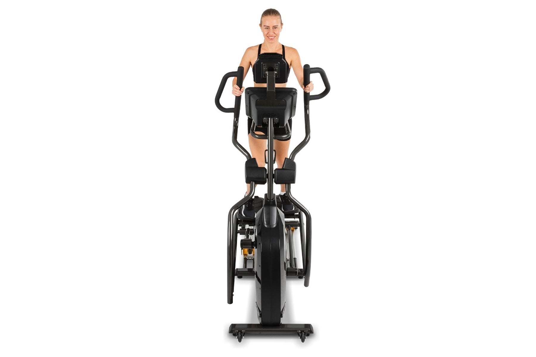 Woman wearing black sports bra on black upright elliptical machine with dual handles against white background