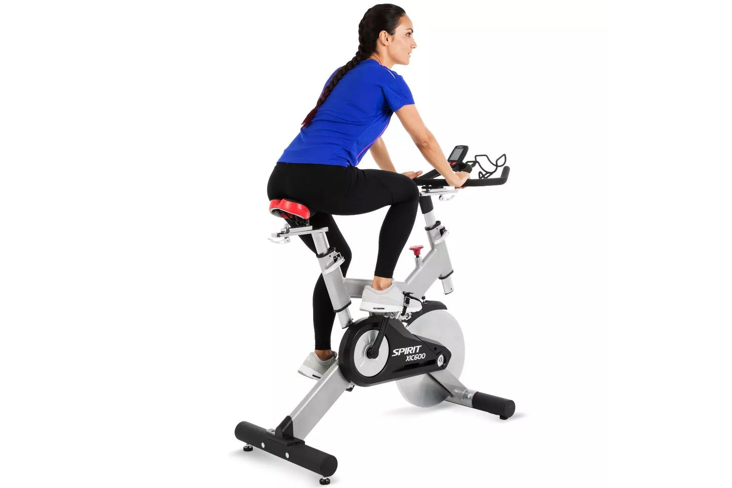Woman wearing blue short-sleeve top and black leggings with red waistband, exercising on Spirit XIC600 stationary indoor bike