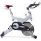 Spirit XIC600 indoor cycle with white frame, black flywheel, red seat and handlebars, on white background