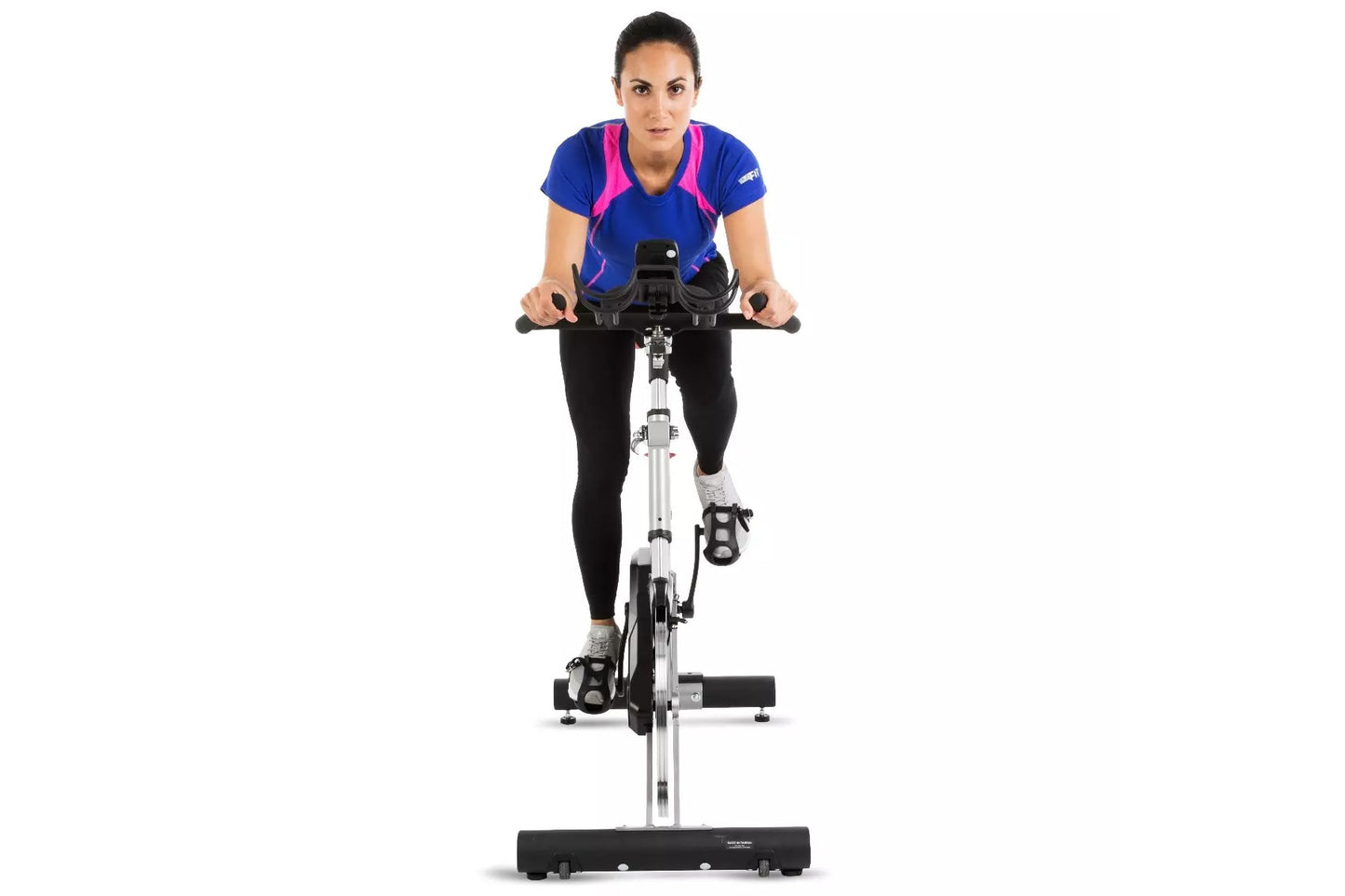 Woman wearing blue and pink athletic top with black leggings, riding white and black stationary indoor exercise bike on white