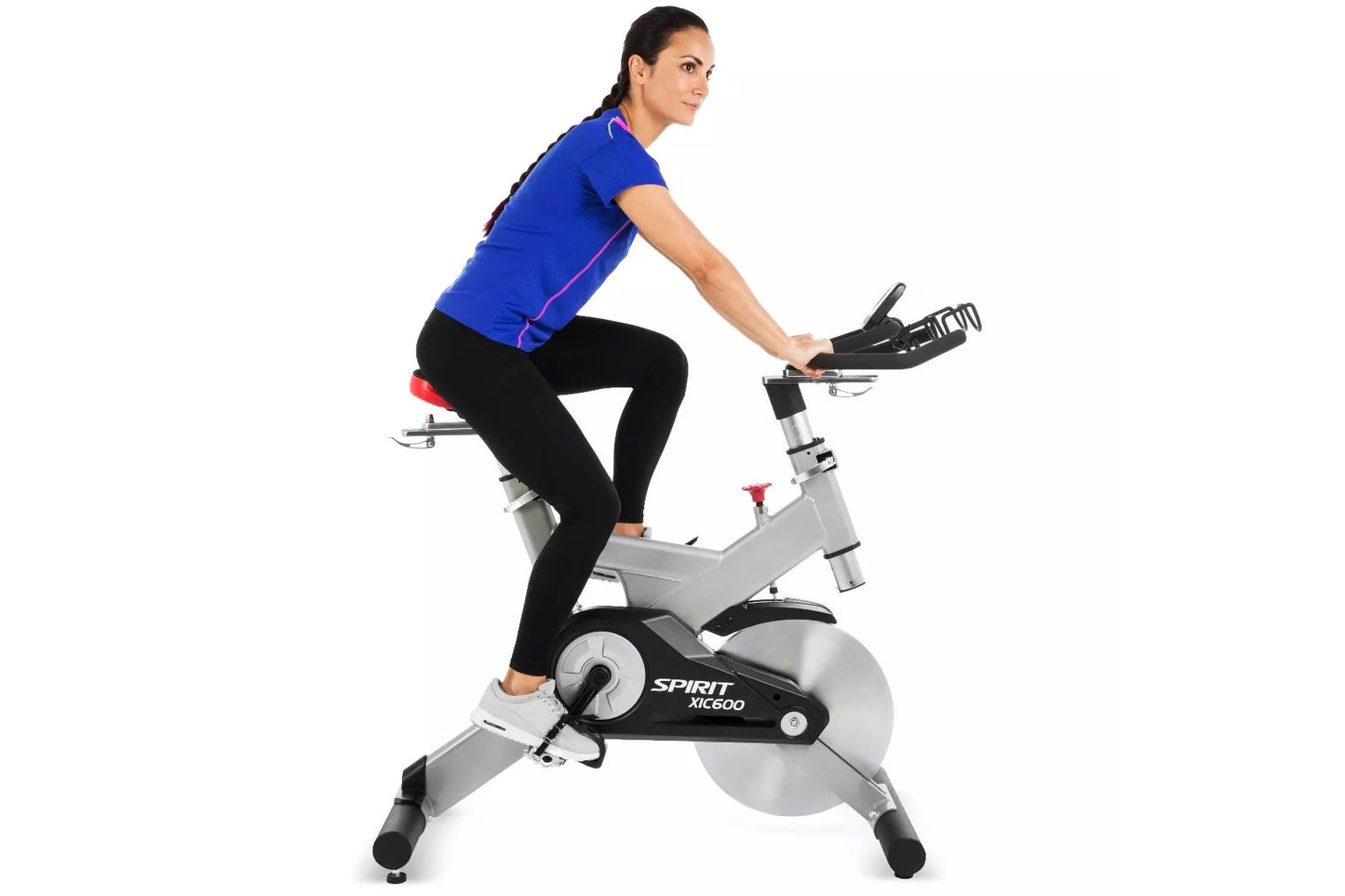 Woman wearing blue short-sleeve top and black leggings on Spirit XIC600 stationary exercise bike with gray frame and black fl