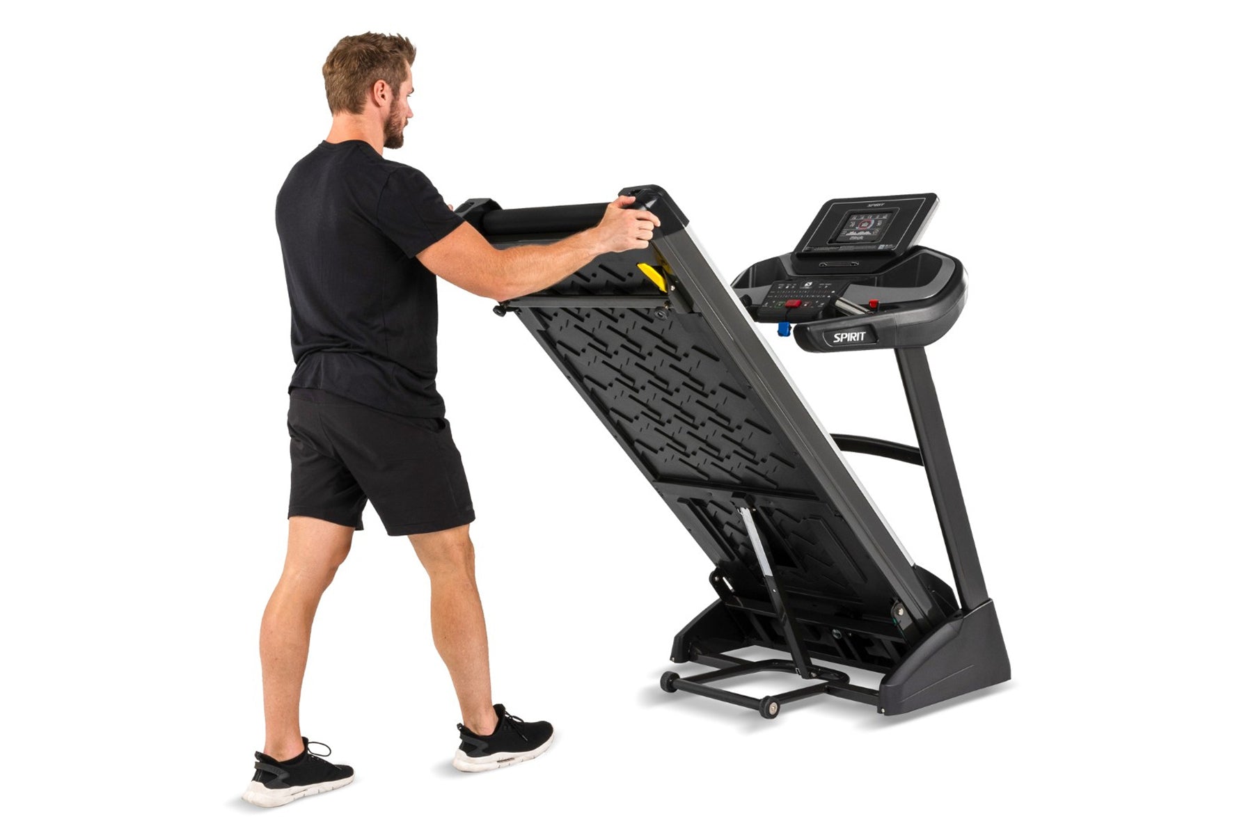 Man in black shirt and shorts running on black Spirit treadmill with digital display, shown from side angle on white backgrou