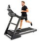Man in black shirt and shorts running on Spirit XT485 treadmill with digital display, white accent stripe on black running de