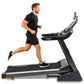 Man in black shirt and shorts running on Spirit XT485 treadmill with digital display, shown from side view on white backgroun