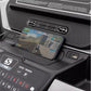 Smartphone displaying racing game on black treadmill console with perforated dashboard and control buttons