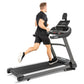 Man in black athletic wear running on Spirit XT685ENT treadmill with digital display, against white background