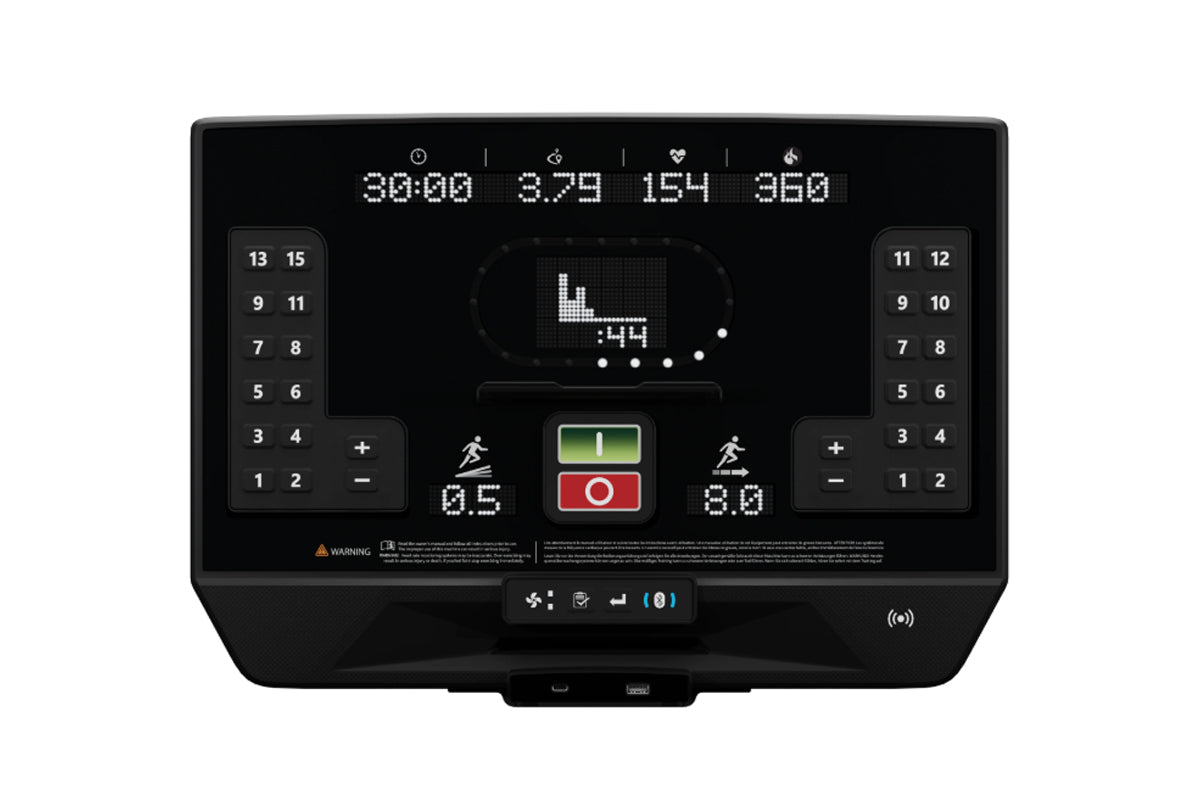Black treadmill console with digital display showing workout metrics, numbered keypads on sides, green and red control button