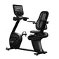 Black Star Trac recumbent exercise bike with integrated touchscreen display, mesh back support, and pedal platform on white b