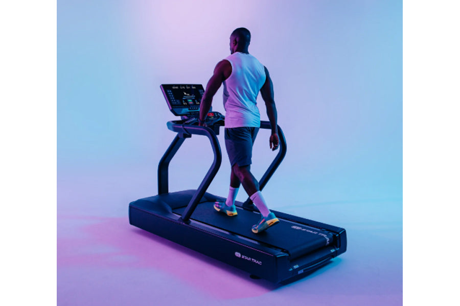 Athlete wearing gradient pink and blue tank top and colorful sneakers running on black Star Trac treadmill with digital displ