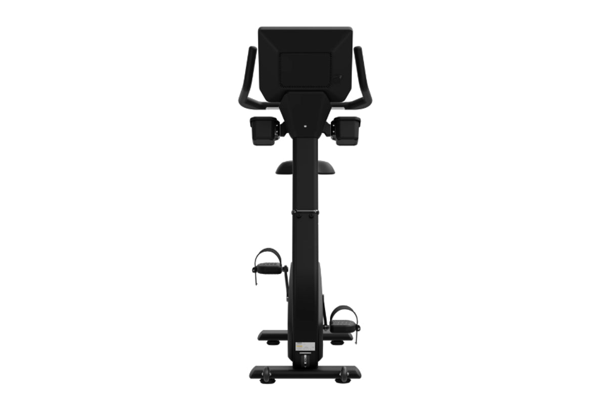 Black upright exercise bike with digital display console, dual handle bars, and pedals with foot straps on white background