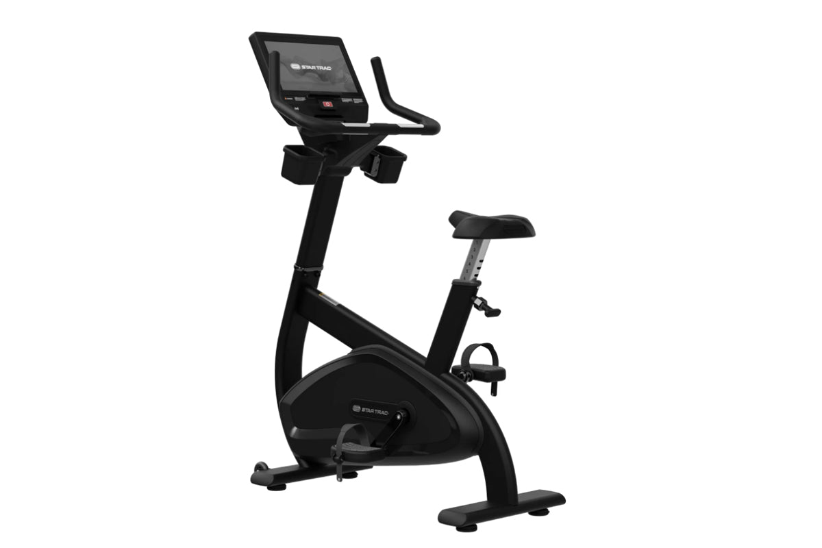 Black upright exercise bike with digital display console, padded seat, handlebars, and foot pedals on white background