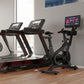 Home gym setup with black and red Star Trac exercise equipment including treadmills, stationary bike, and digital displays on