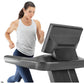 Woman running on black and gray Freemotion T22.9 REFLEX treadmill with digital display, wearing white tank top and blue leggi