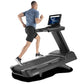 Man running on black Freemotion t22.9 REFLEX treadmill with tablet display, worn by model on white background