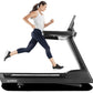 Woman running on black Freemotion t22.9 REFLEX treadmill, wearing white tank top and navy leggings