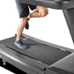 Man running on Freemotion t22.9 REFLEX treadmill with black belt and gray frame, white sneakers visible