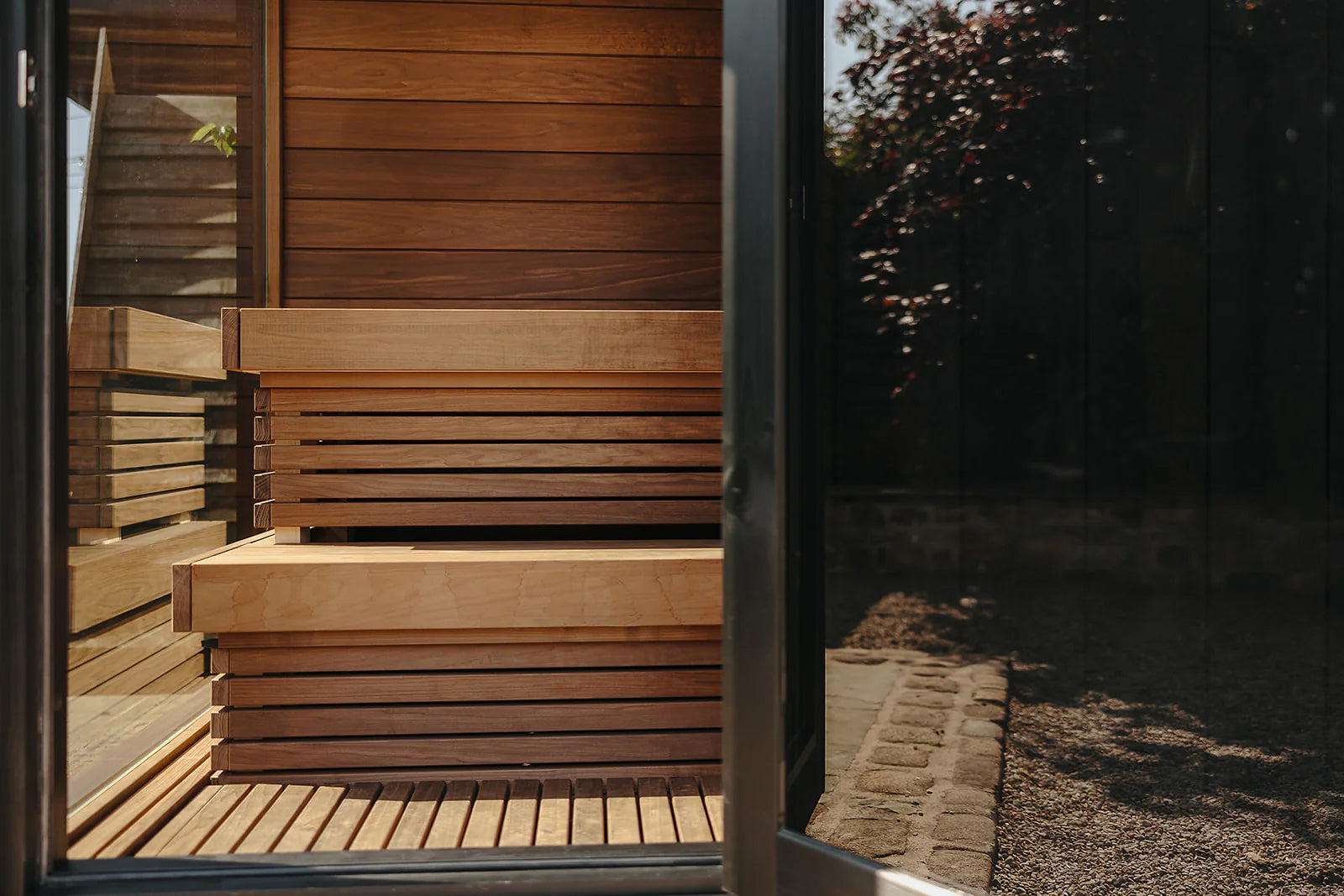 Thermasol Nordic Misty outdoor sauna with light wood interior, horizontal slat benches, and open door view of garden setting