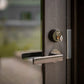 Modern stainless steel door handle and black Abloy Active smart lock on dark wood sauna door