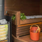 Harvia wood-burning sauna stove with yellow glass front and hot stones inside wooden sauna room with benches and accessories