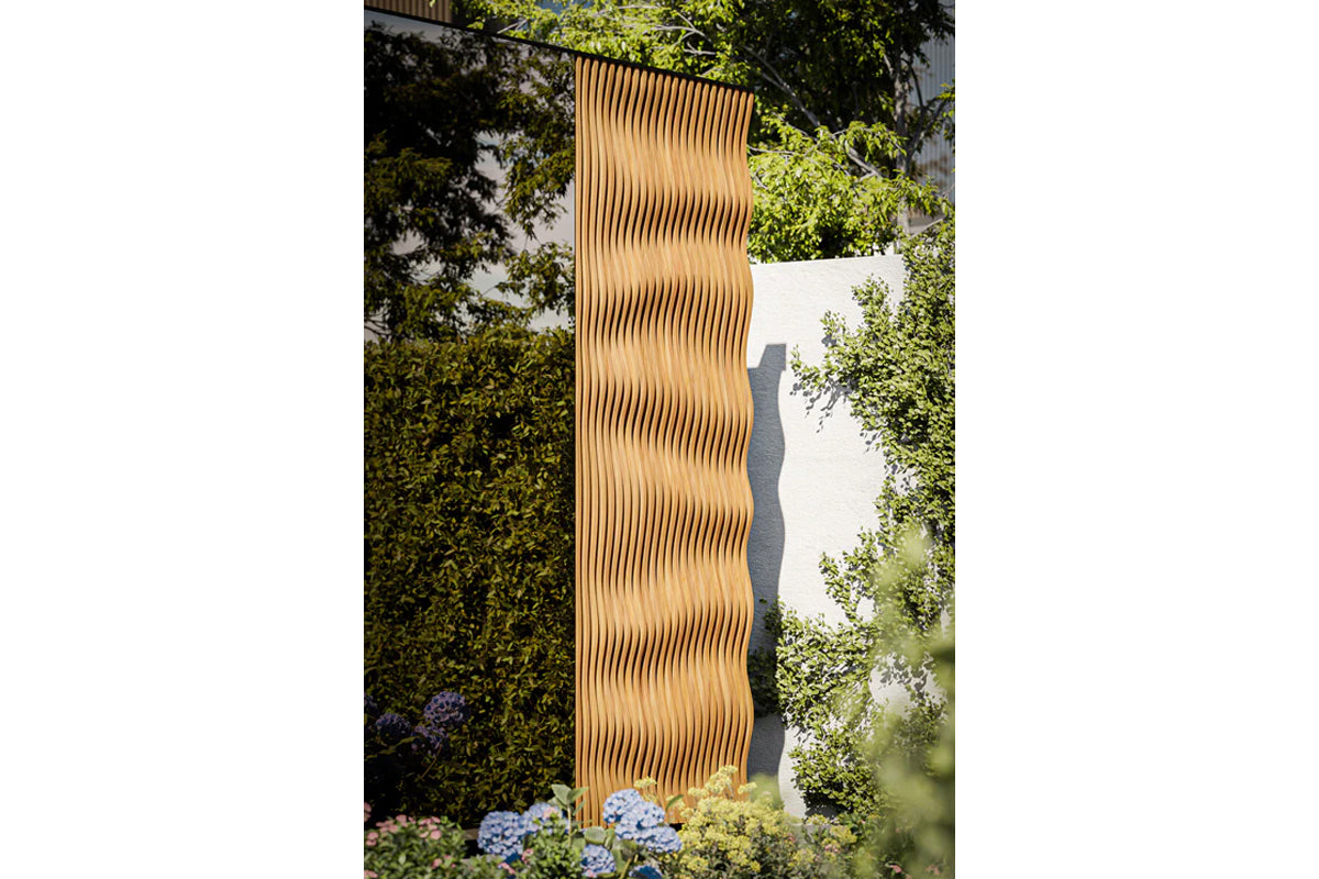 Natural wood vertical slatted outdoor sauna with wavy rippled surface in garden setting surrounded by green foliage
