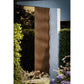 Thermasol Ombra outdoor sauna with vertical wavy wood slats, displayed in garden setting with surrounding greenery and blue b
