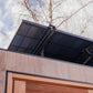 Black solar panel roof on modern outdoor sauna with wood siding and copper door frame