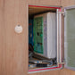 Open electrical panel with white distribution box, green door, and red frame mounted on wood wall