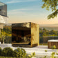 Modern outdoor sauna with golden vertical wood slats and glass doors on elevated terrace overlooking landscape