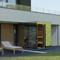 Modern outdoor sauna with lime-green moss wall panel, wood slat accents, open wooden door, and adjacent wooden lounge chair o