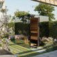 Modern outdoor sauna with glass and wood panels, black metal frame, wooden interior, set in garden with purple flowering vine