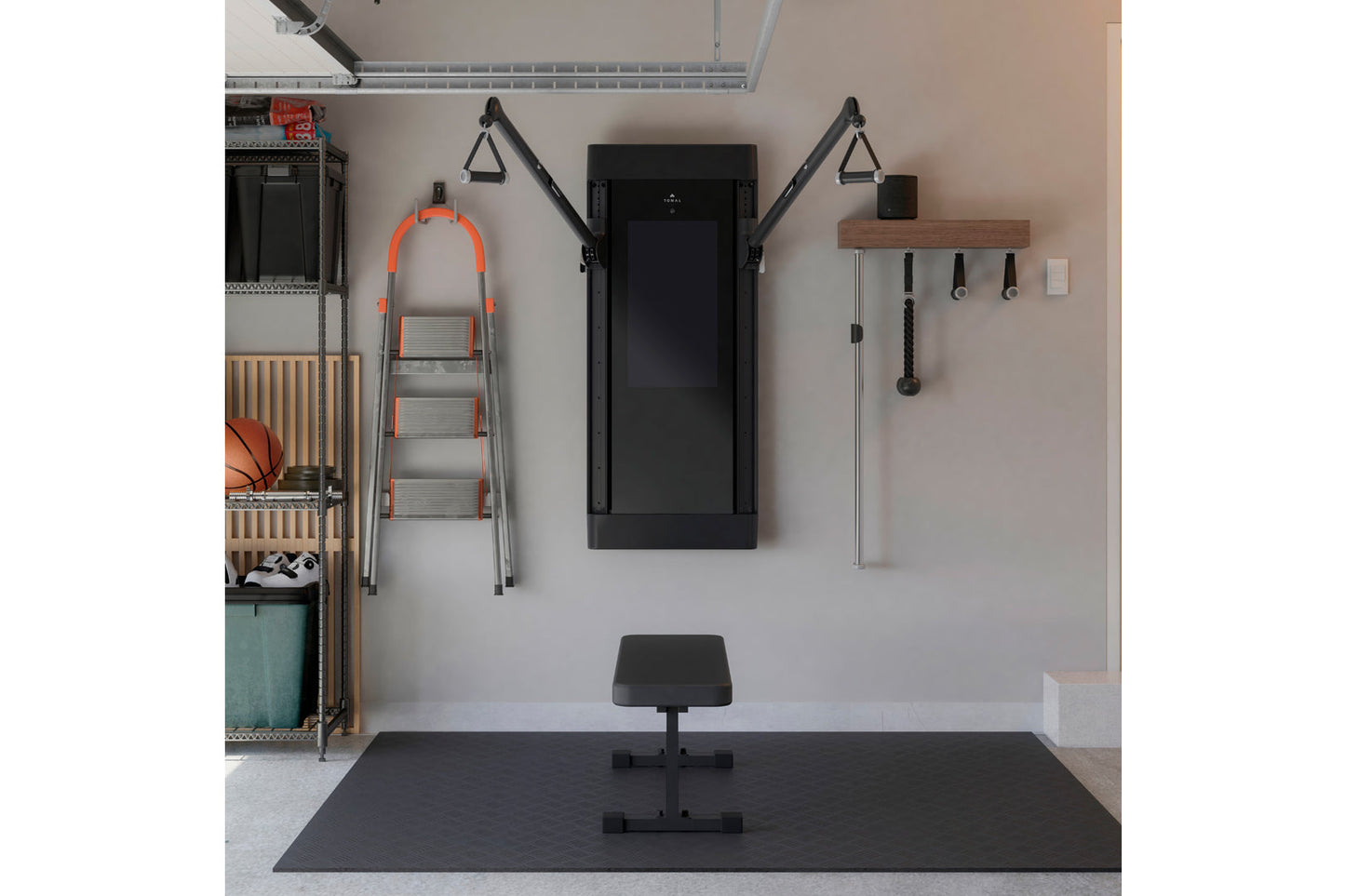 Home gym setup with black Tonal smart fitness machine mounted on wall, orange and gray ladder, black weight bench, wooden she
