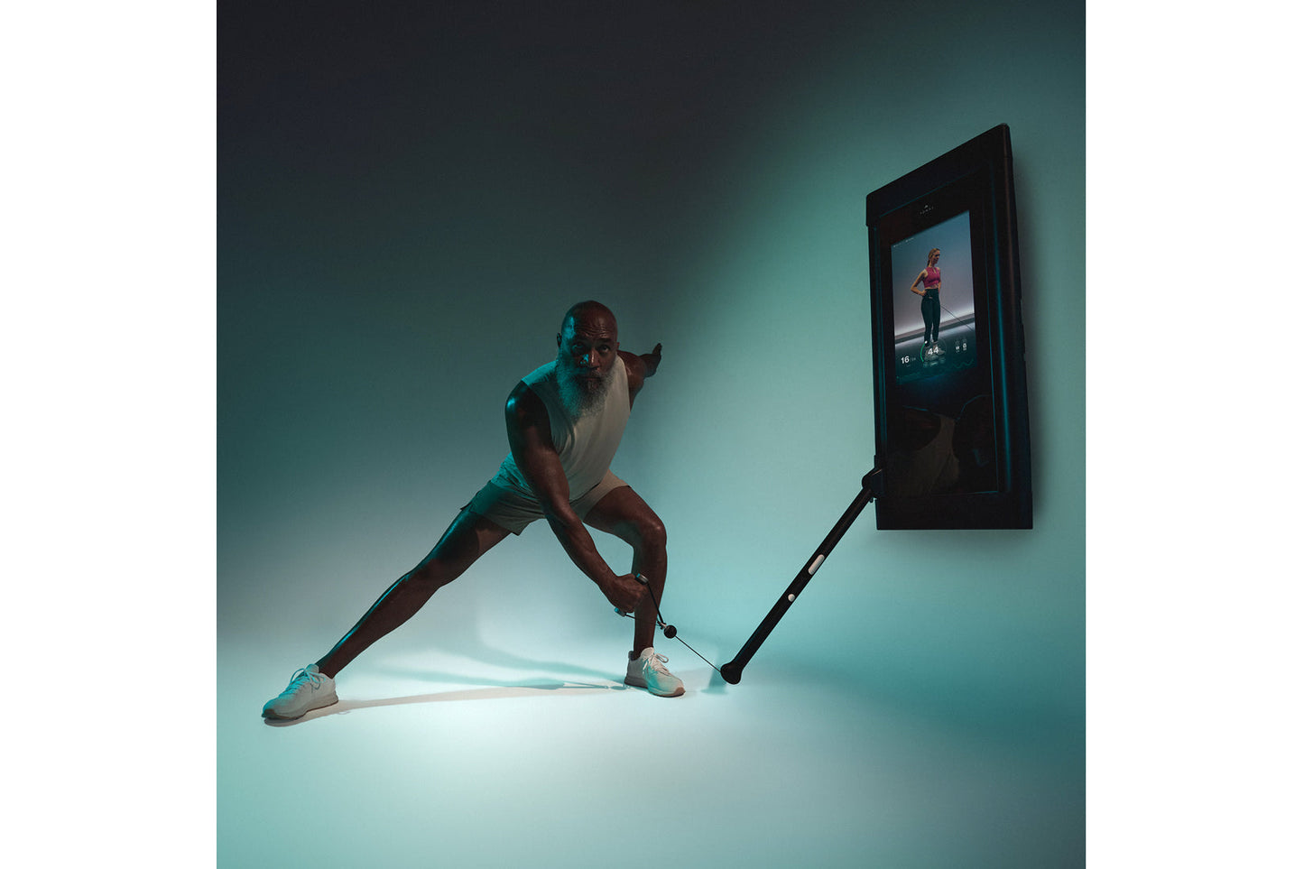 Man in white tank top and black shorts doing a lunge exercise with Tonal 2 smart home gym against teal background