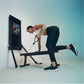Man using black Tonal 2 Smart Home Gym with digital screen, performing resistance exercise on bench against blue gradient bac