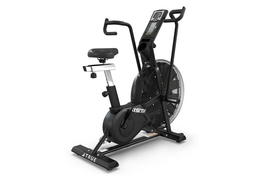 Black TRUE ADX exercise air bike with large fan wheel, digital display console, curved handlebars, black cushioned seat, and 