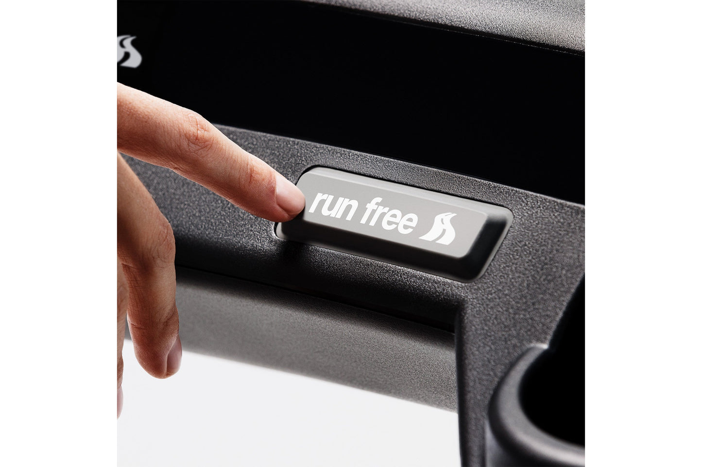 Hand pressing "run free" button on black and gray KICKR RUN smart treadmill control panel