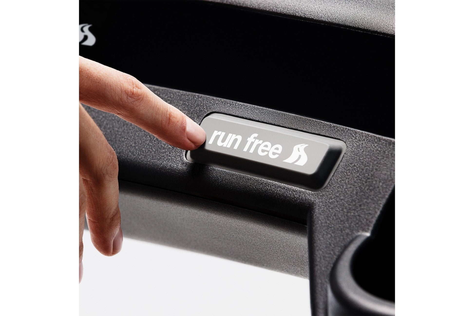 Hand pressing "run free" button on black and gray KICKR RUN smart treadmill control panel