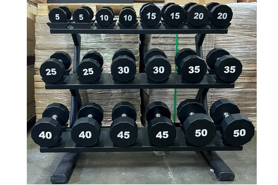 Black rubber dumbbell rack with three tiers holding pairs of weights labeled 5 to 50 pounds, on concrete floor