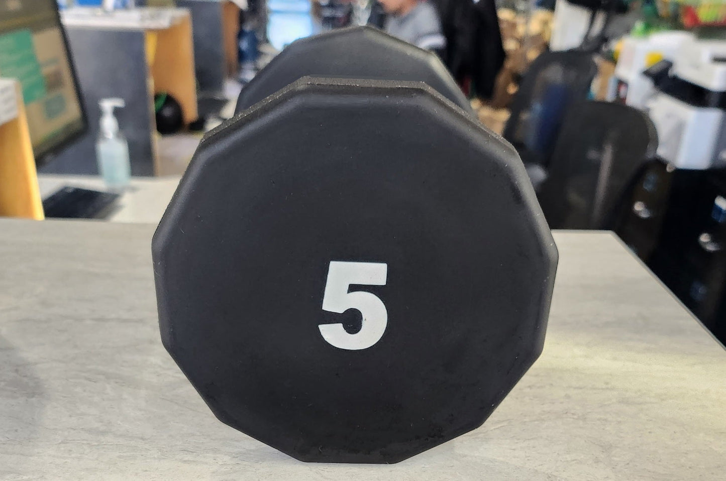 Black 5-pound urethane dumbbell with white number marking, 12-sided shape, on white surface