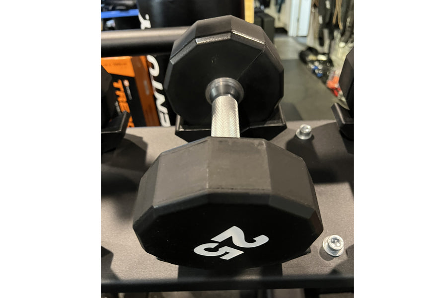 Warrior black 12-sided urethane dumbbell with white logo on hexagonal head and chrome handle, displayed on rack
