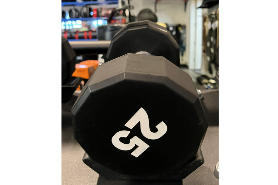 Black 50-pound 12-sided urethane dumbbell with white number marking, in gym setting