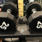 Pair of black 25-pound hexagonal dumbbells with white numbers on gray stand in gym setting