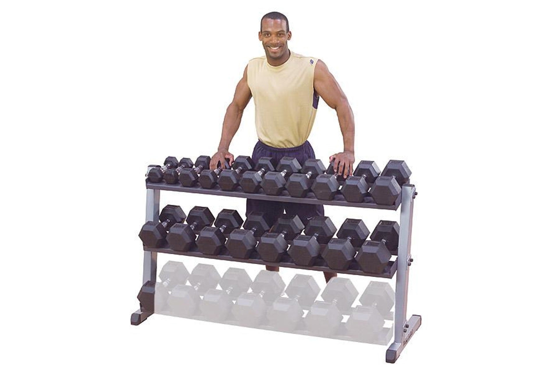 Man wearing cream tank top and navy shorts standing behind three-tier dumbbell rack with black hexagon dumbbells on upper two