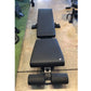 Black padded flat incline decline weight bench with adjustable backrest and leg extension, viewed from above on concrete floo