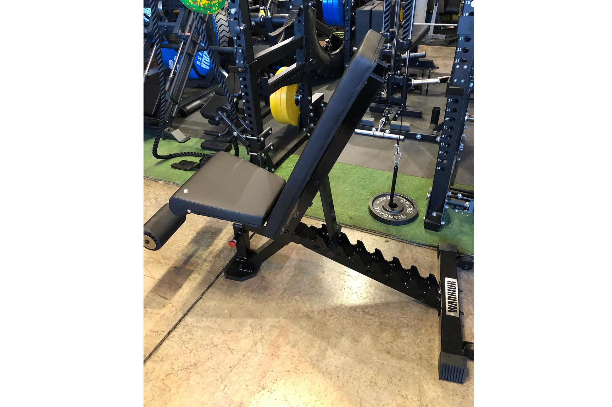 Black and gray weight bench with adjustable backrest, footrest, and black metal frame in gym setting