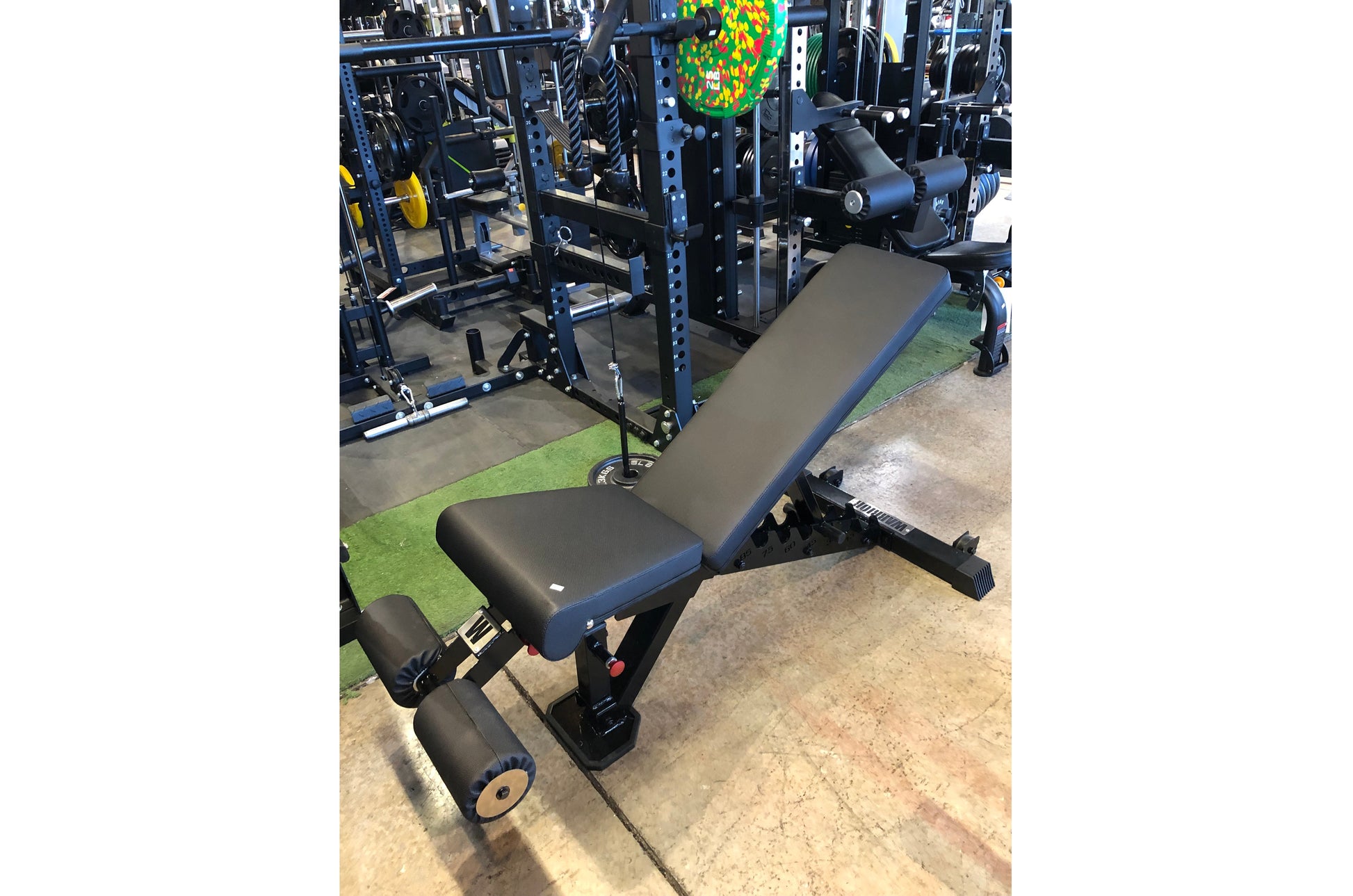 Black and blue adjustable weight bench with incline and decline positions, leg extension attachment, displayed in gym setting