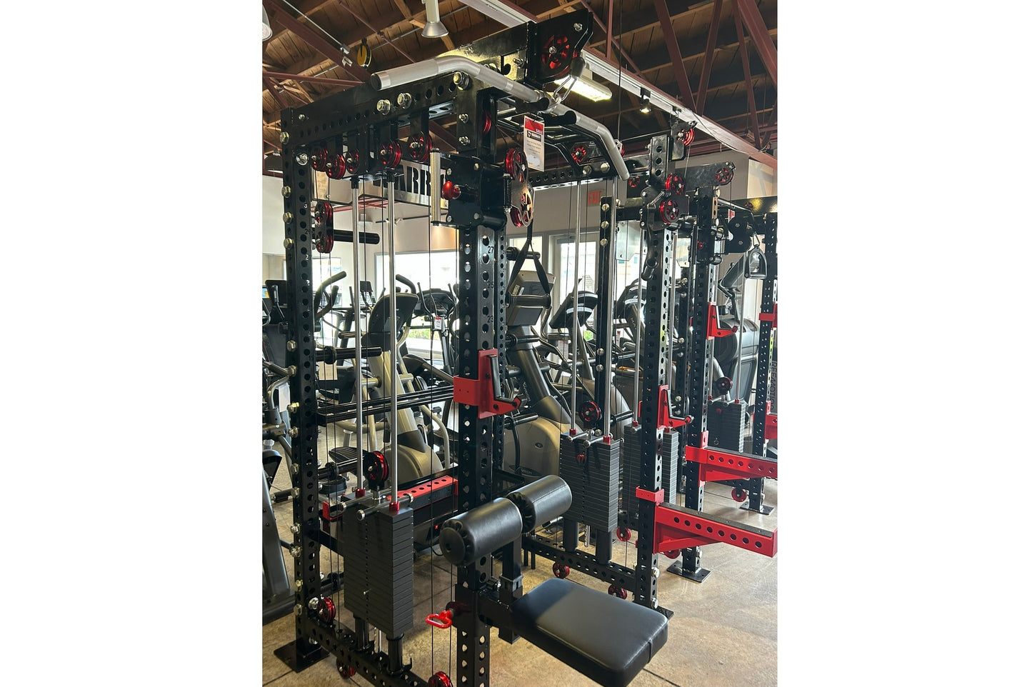 Black and red steel cable crossover power rack system with dual weight stacks, lat pulldown attachment, and adjustable pulley