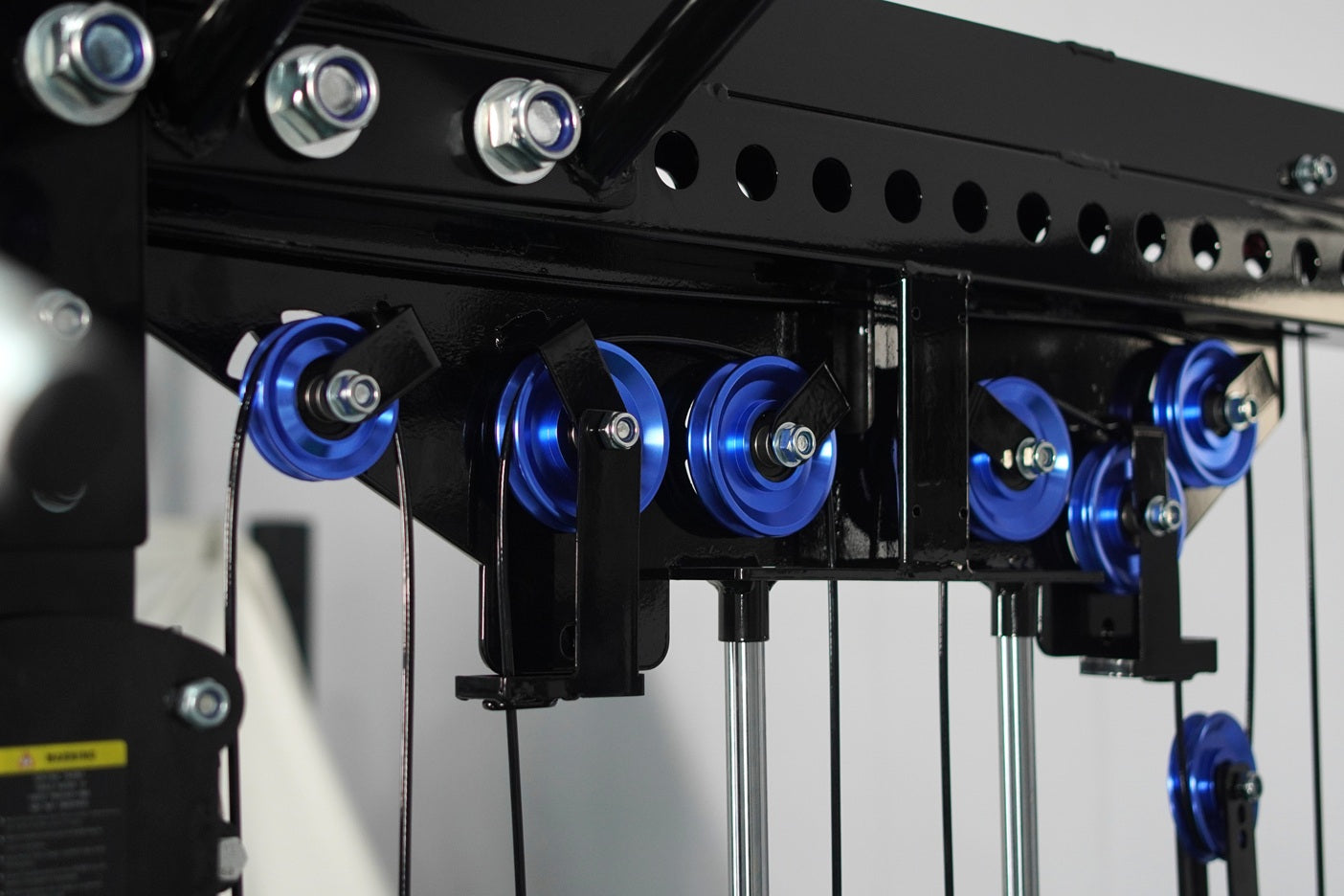 Black cable crossover machine with blue dual pulleys, chrome handles, and adjustable weight pegs on white background
