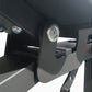 Black and gray adjustable weight bench with leg extension attachment and circular dial mechanism, shown from side angle
